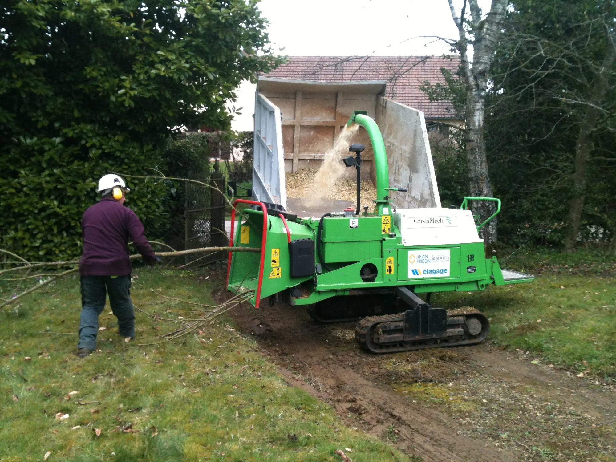 Élagueur alimentant une broyeuse de branches sur chenilles